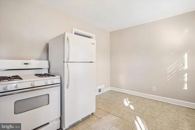 a kitchen with a stove a refrigerator and white cabinets