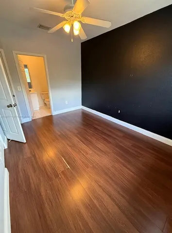 a view of empty room with wooden floor and fan