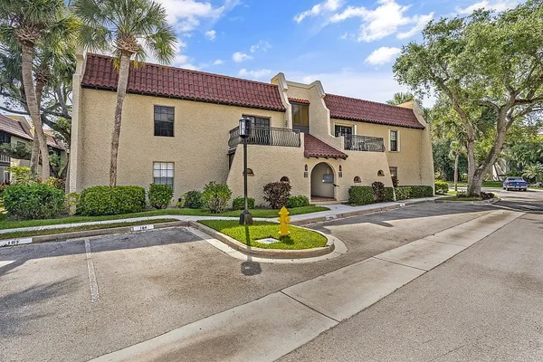 a view of a white house with a swimming pool and a lawn chairs under an umbrella