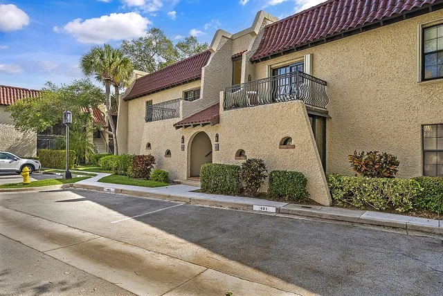 a view of a white house with a yard and table and chairs under an umbrella