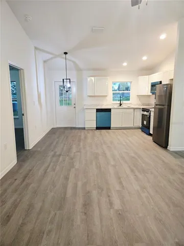 a view of kitchen with refrigerator microwave and stove with wooden floor