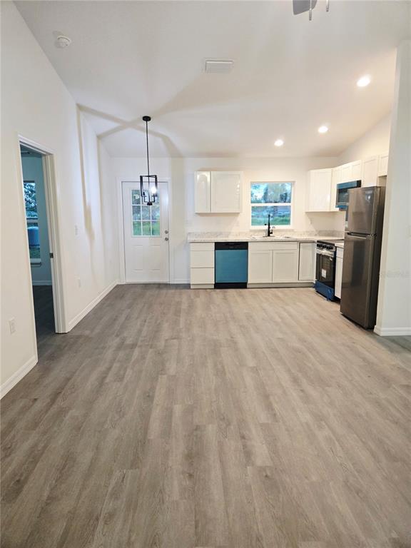 228 Juniper Loop Circle Ocala, FL 34480 - Photo 2 of 4 a view of kitchen with refrigerator microwave and stove with wooden floor