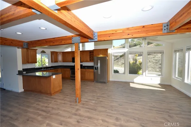 a view of kitchen with stainless steel appliances wooden floor and dining table