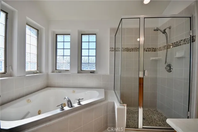 a bathroom with a tub a window and a glass door shower