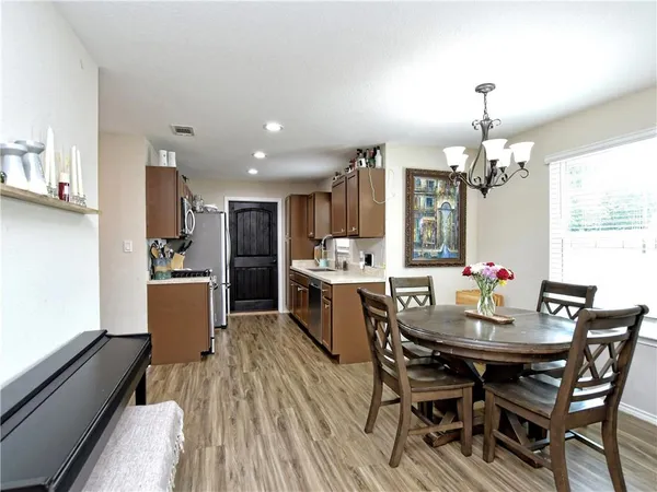 a kitchen with a dining table chairs stainless steel appliances and cabinets