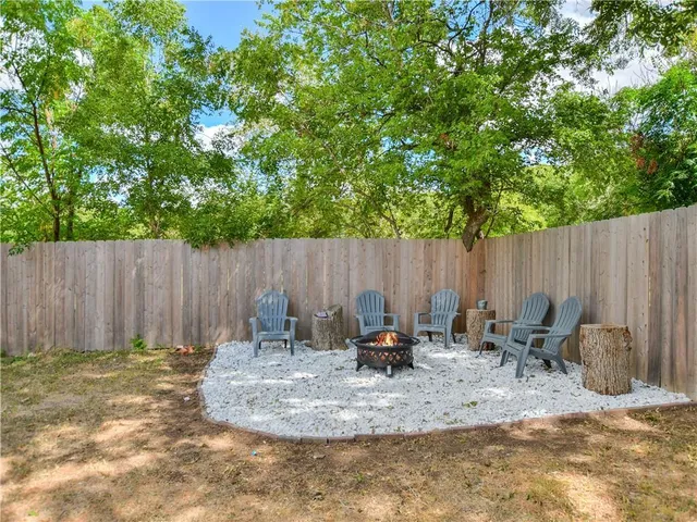 a backyard of a house with lawn chairs and a fire pit