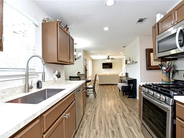 a kitchen with granite countertop a sink a counter space appliances and cabinets