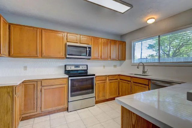 a kitchen with stainless steel appliances granite countertop wooden cabinets a stove top oven a sink and dishwasher