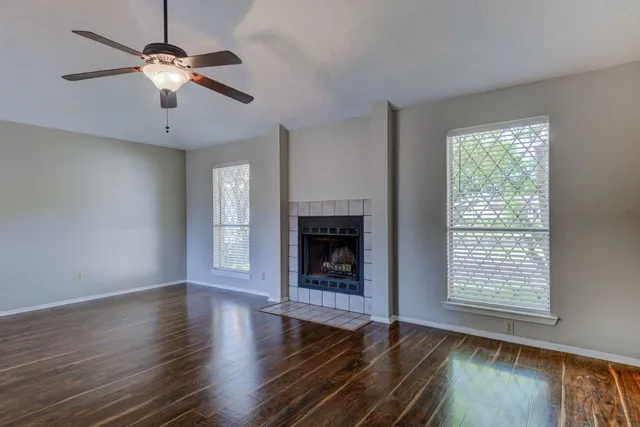 a view of an empty room with wooden floor fireplace and a window