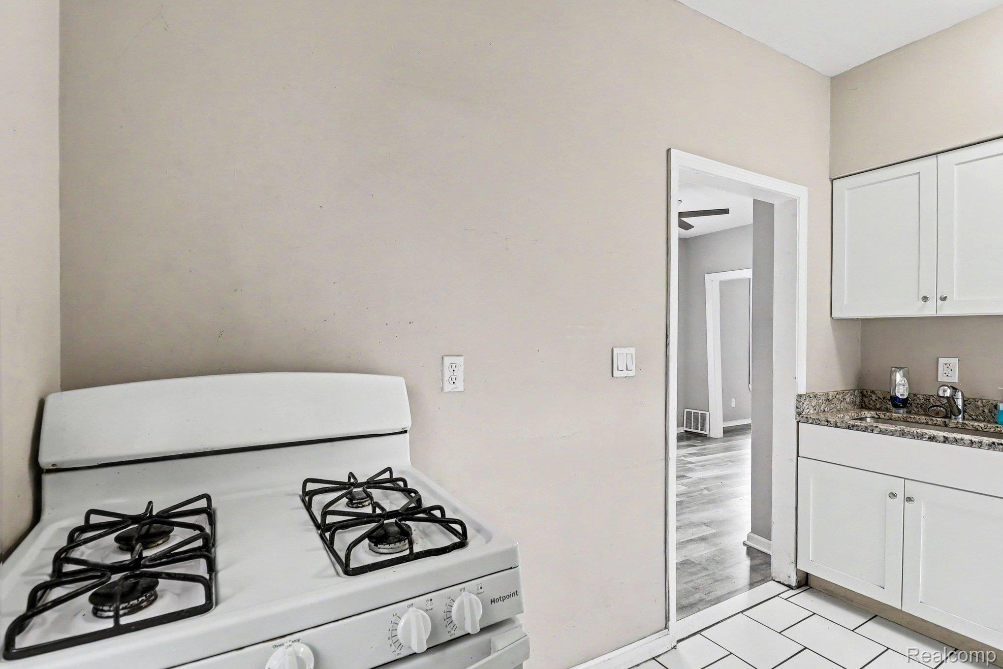 7743 Pitt Street Detroit, MI 48209 - Photo 9 of 15 Kitchen featuring a white gas range, white cabinetry, and a speckled countertop