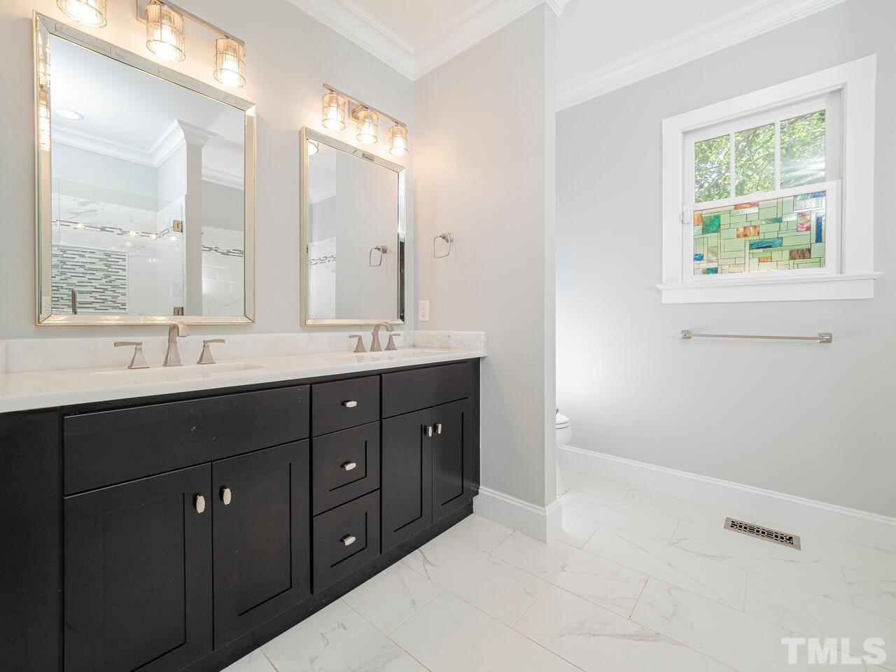 910 South Person Street Raleigh, NC 27601 - Photo 16 of 30 a bathroom with a double vanity sink a large mirror a bathtub and window