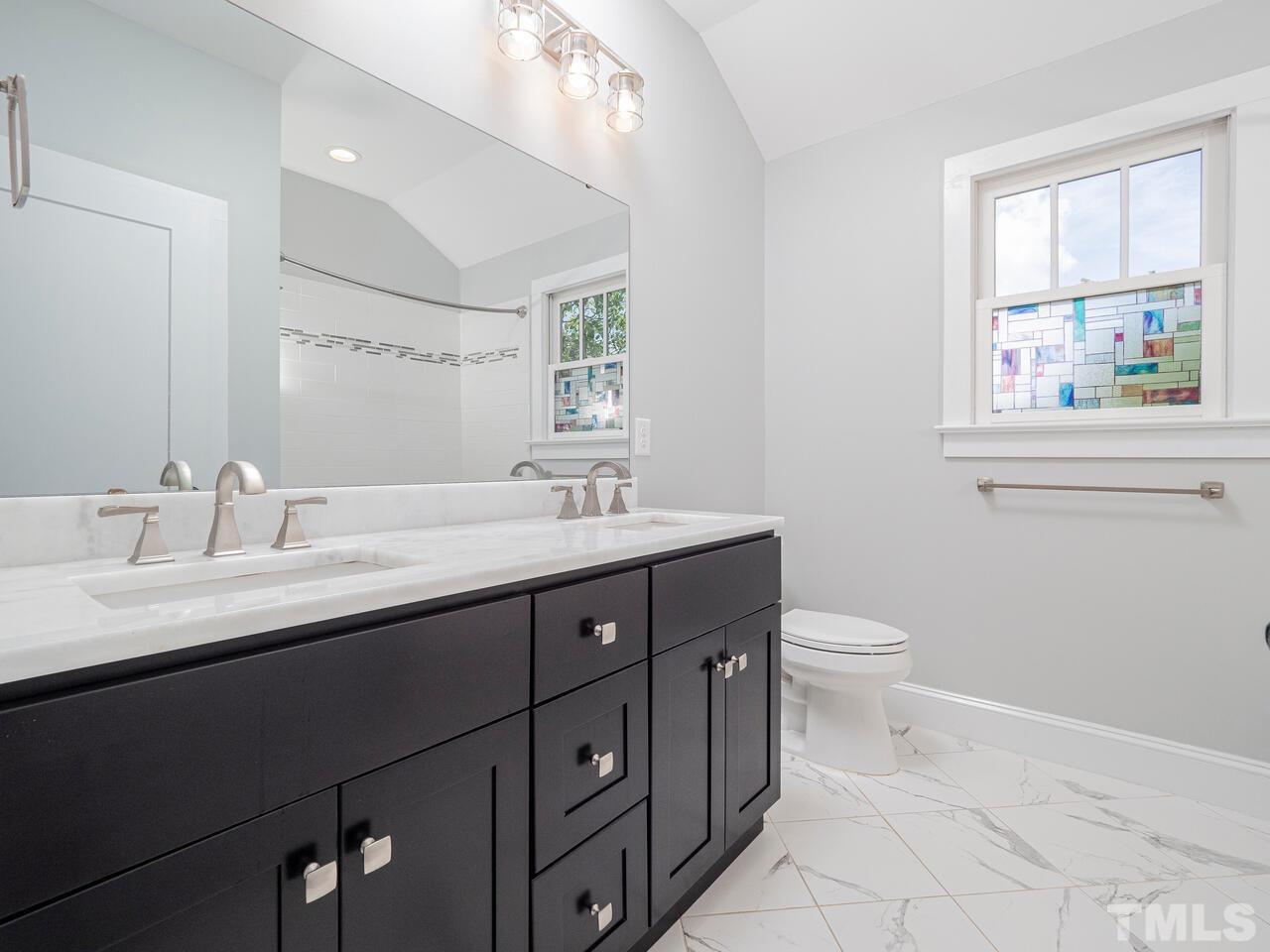 910 South Person Street Raleigh, NC 27601 - Photo 22 of 30 a bathroom with a double vanity sink toilet and a window
