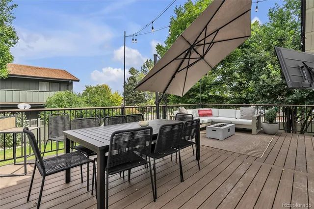 a view of deck with table and chairs a barbeque with wooden floor and fence