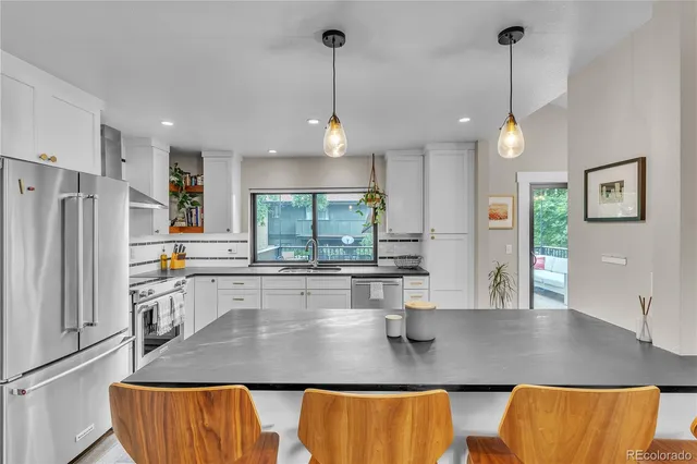 a kitchen with stainless steel appliances granite countertop a sink a refrigerator and a counter top space