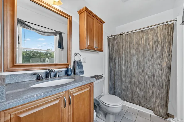 a bathroom with a granite countertop sink toilet and mirror