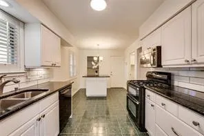 a kitchen with granite countertop a sink a stove cabinets and counter space