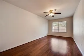 an empty room with wooden floor chandelier fan and windows