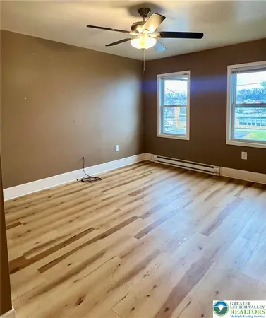 a view of a big room with wooden floor and windows