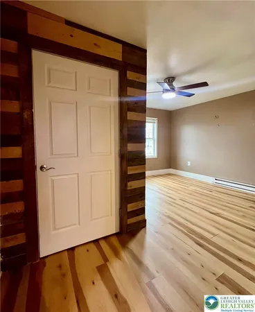 a view of empty room with wooden floor and fan