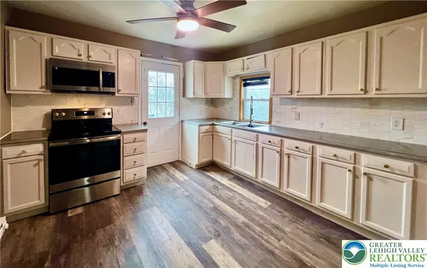 a kitchen with stainless steel appliances granite countertop a stove top oven a sink dishwasher a refrigerator and cabinets with wooden floor