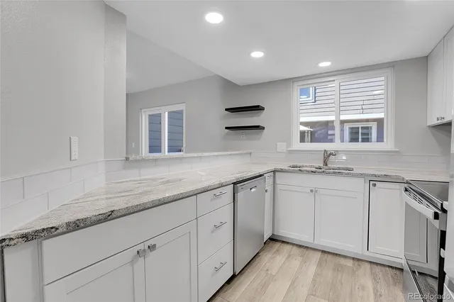 a kitchen with granite countertop white cabinets and a sink