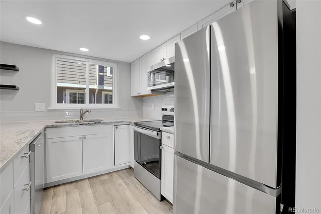 a kitchen with stainless steel appliances granite countertop a refrigerator sink and stove