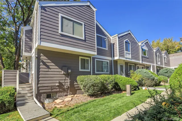 a view of a house with brick walls plants and large tree