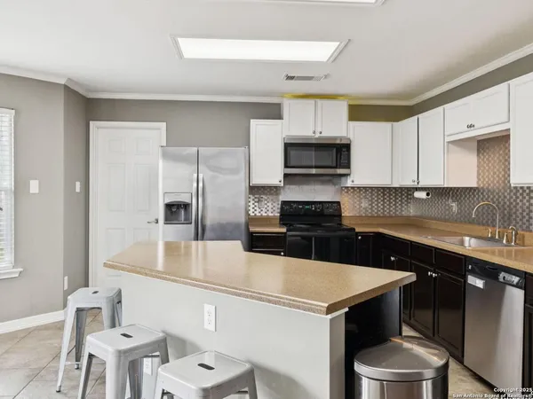 a kitchen with stainless steel appliances a refrigerator a sink a stove a microwave and wooden cabinets