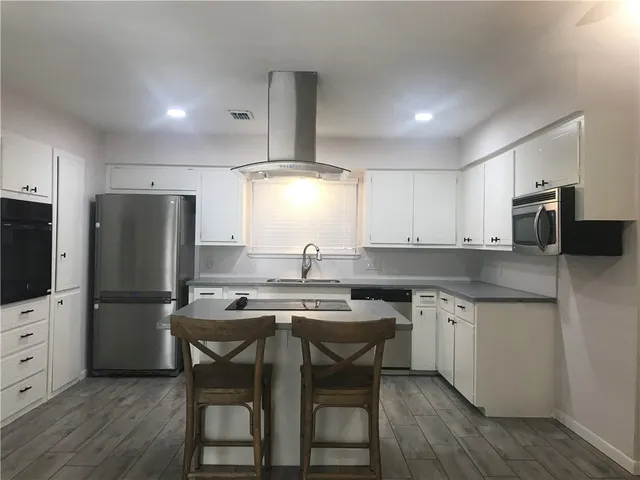 a kitchen with stainless steel appliances granite countertop a table chairs microwave and refrigerator