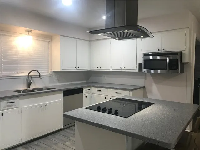 a kitchen that has a sink a stove and cabinets
