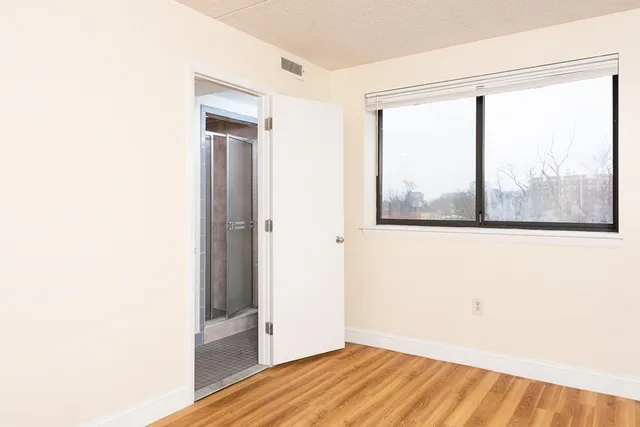 a view of empty room with wooden floor and fan