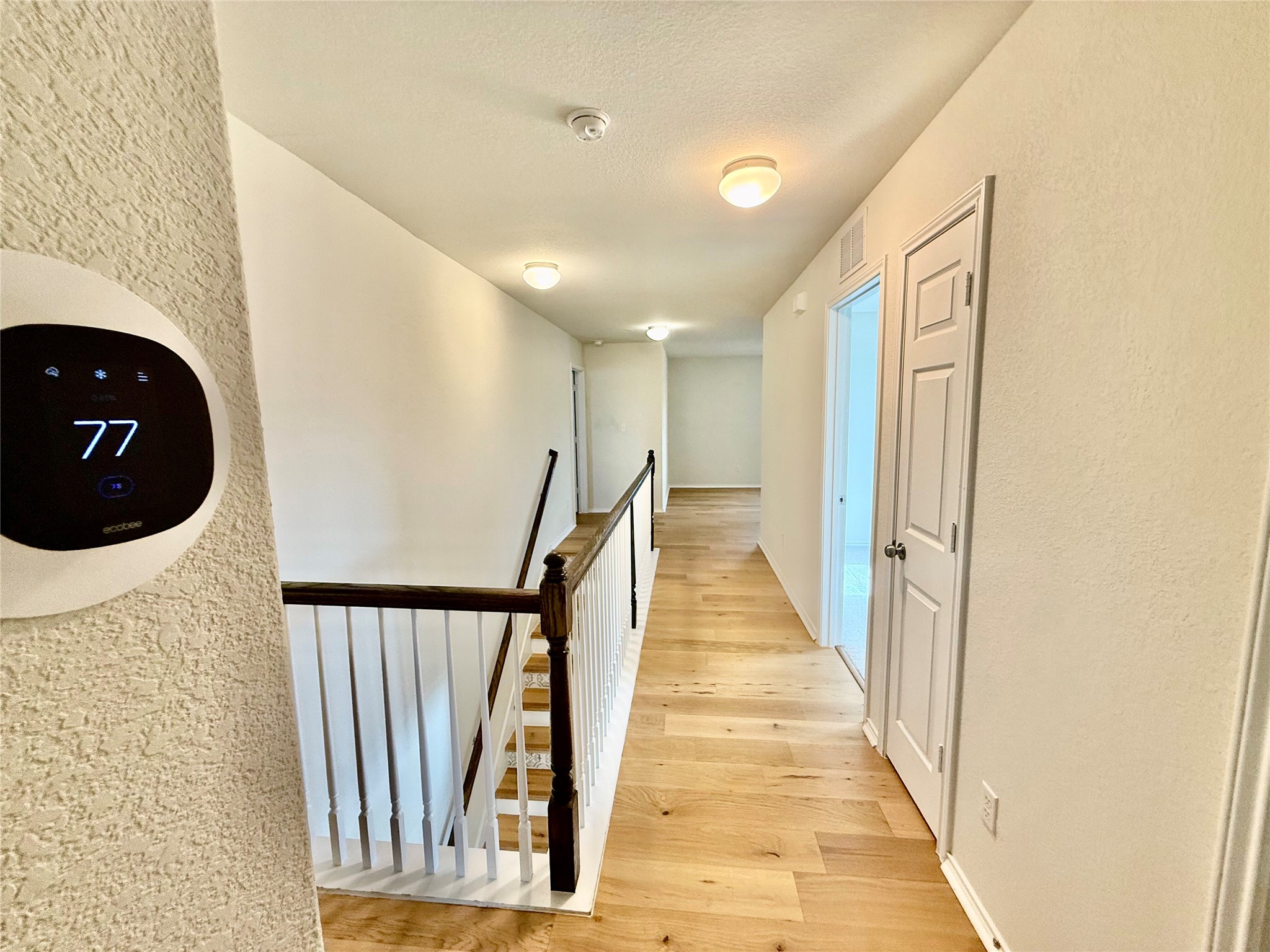 1017 Cliffbrake Way Georgetown, TX 78626 - Photo 18 of 21 Hall featuring a textured wall, light wood-style floors, and an upstairs landing