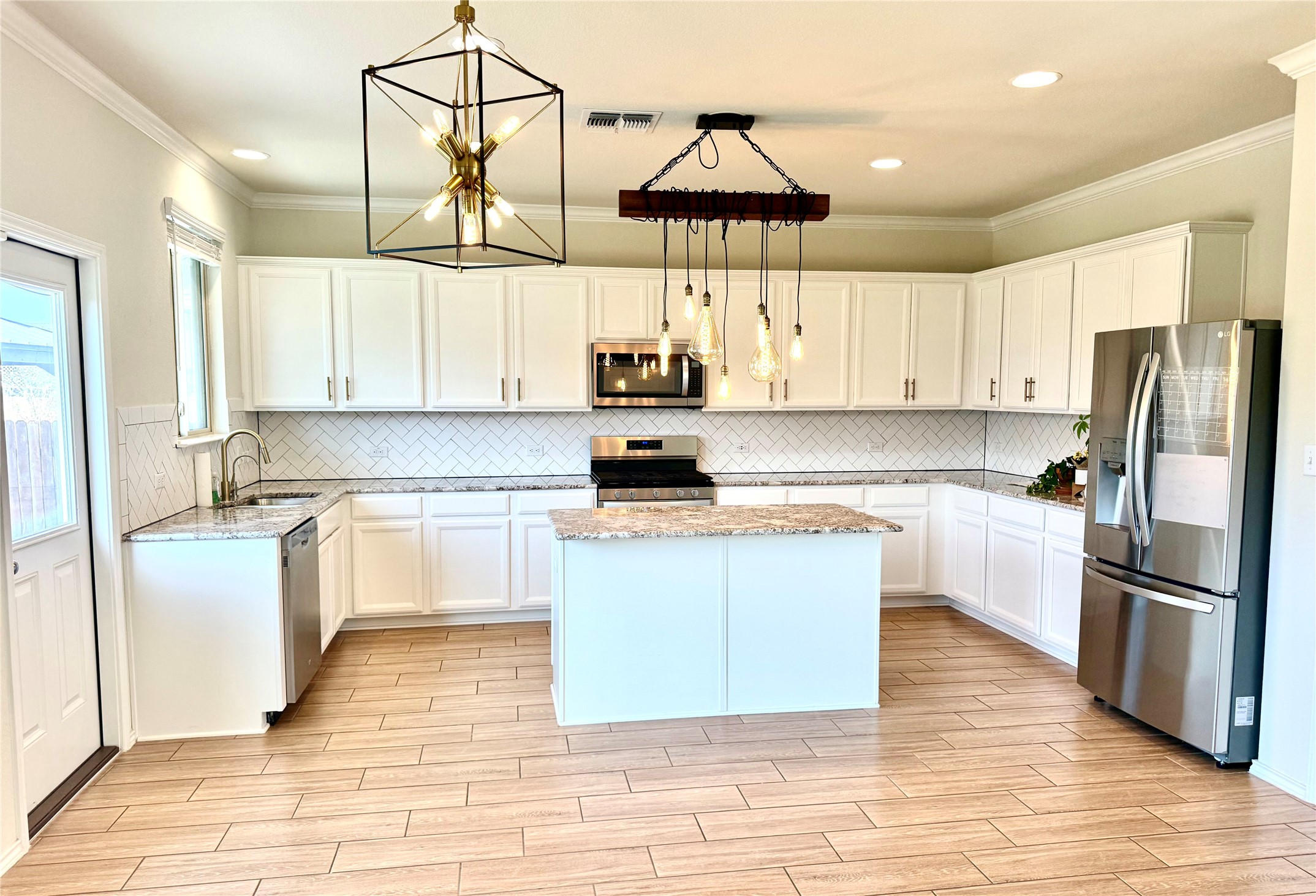 1017 Cliffbrake Way Georgetown, TX 78626 - Photo 9 of 21 Kitchen with stainless steel appliances, white cabinetry, wood tiled floors, a kitchen island, and crown molding