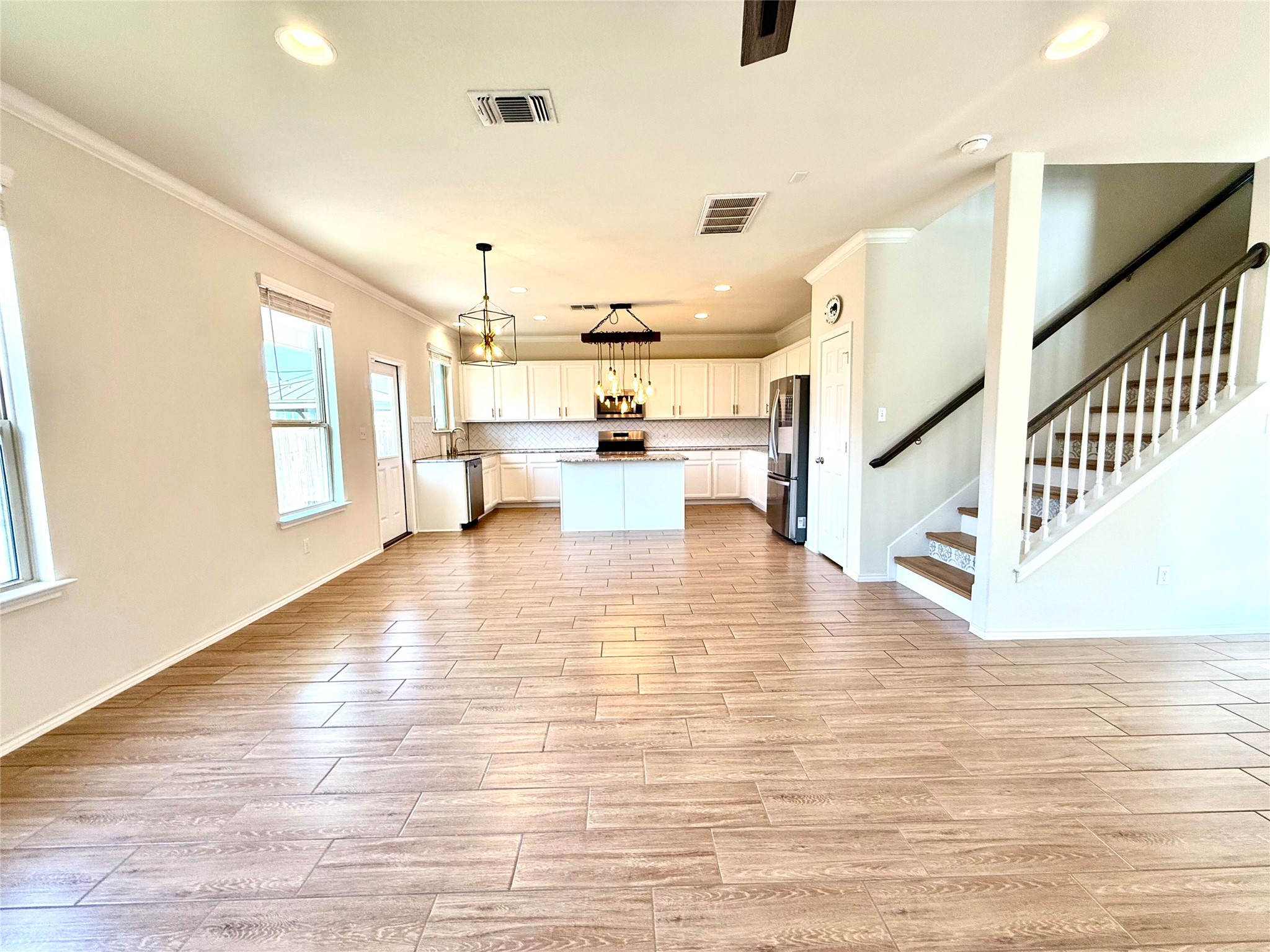 1017 Cliffbrake Way Georgetown, TX 78626 - Photo 21 of 21 Kitchen with white cabinets, wood tiled floors, a center island, open floor plan, and ornamental molding