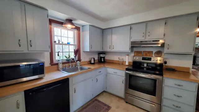 a kitchen with cabinets appliances a sink and a window