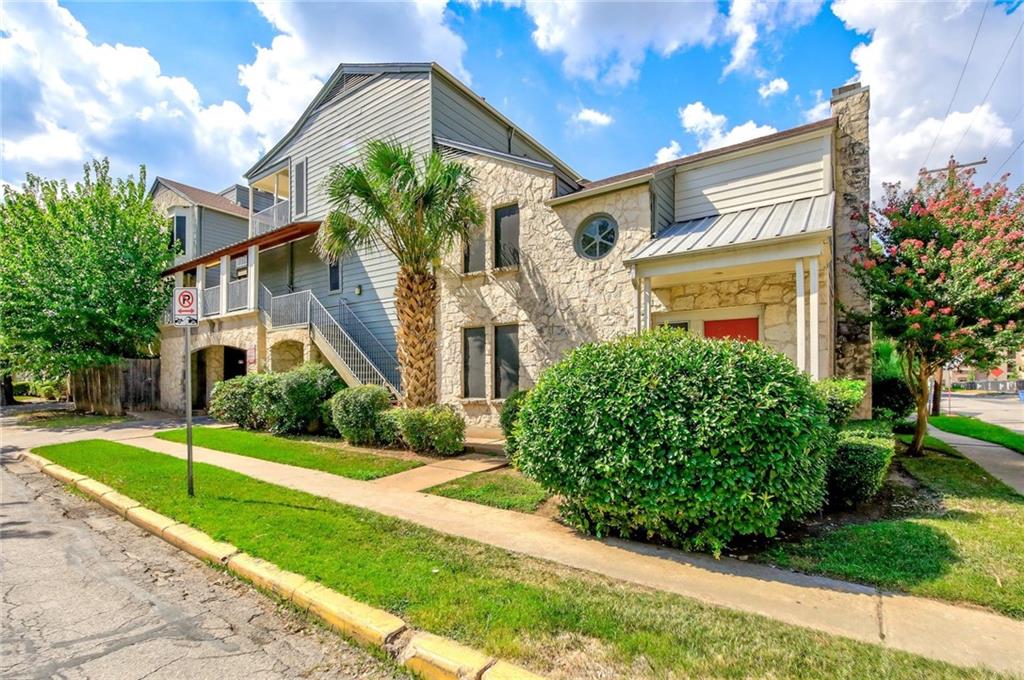 2529 Rio Grande Street, Unit 93 Austin, TX 78705 - Photo 2 of 19 The property features stone and siding exteriors, a prominent stone chimney, and a variety of mature landscaping including a palm tree and shrubs