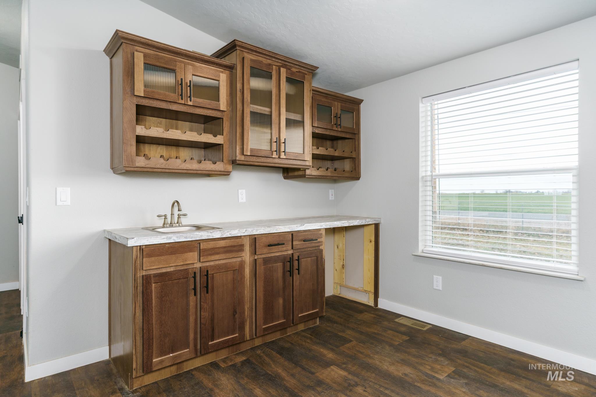 13678 North Hawthorne Road Pocatello, ID 83202 - Photo 11 of 37 Bar featuring light countertops, open shelves, glass insert cabinets, and brown cabinetry