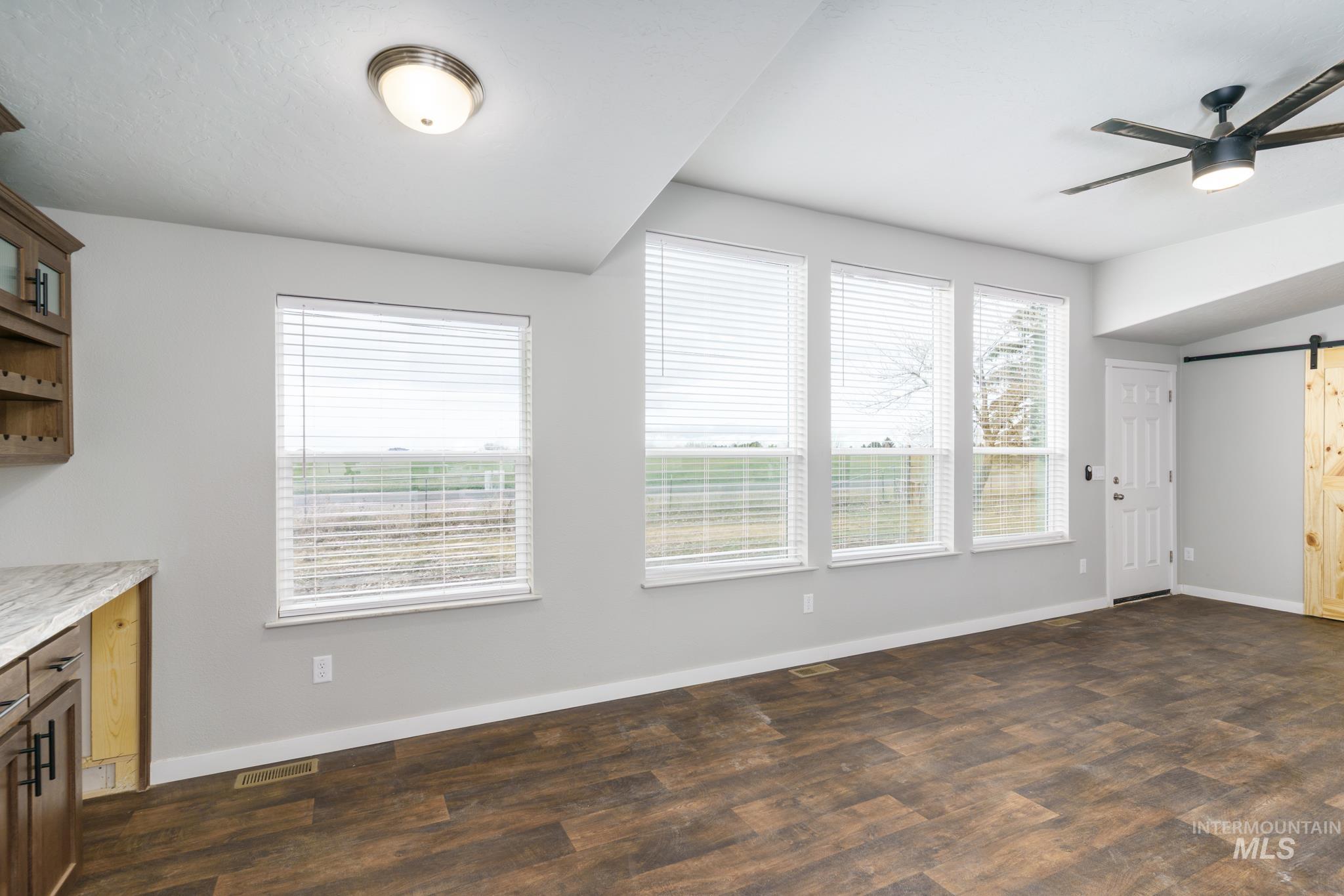 13678 North Hawthorne Road Pocatello, ID 83202 - Photo 14 of 37 Unfurnished dining area with a barn door, a ceiling fan, and dark wood finished floors