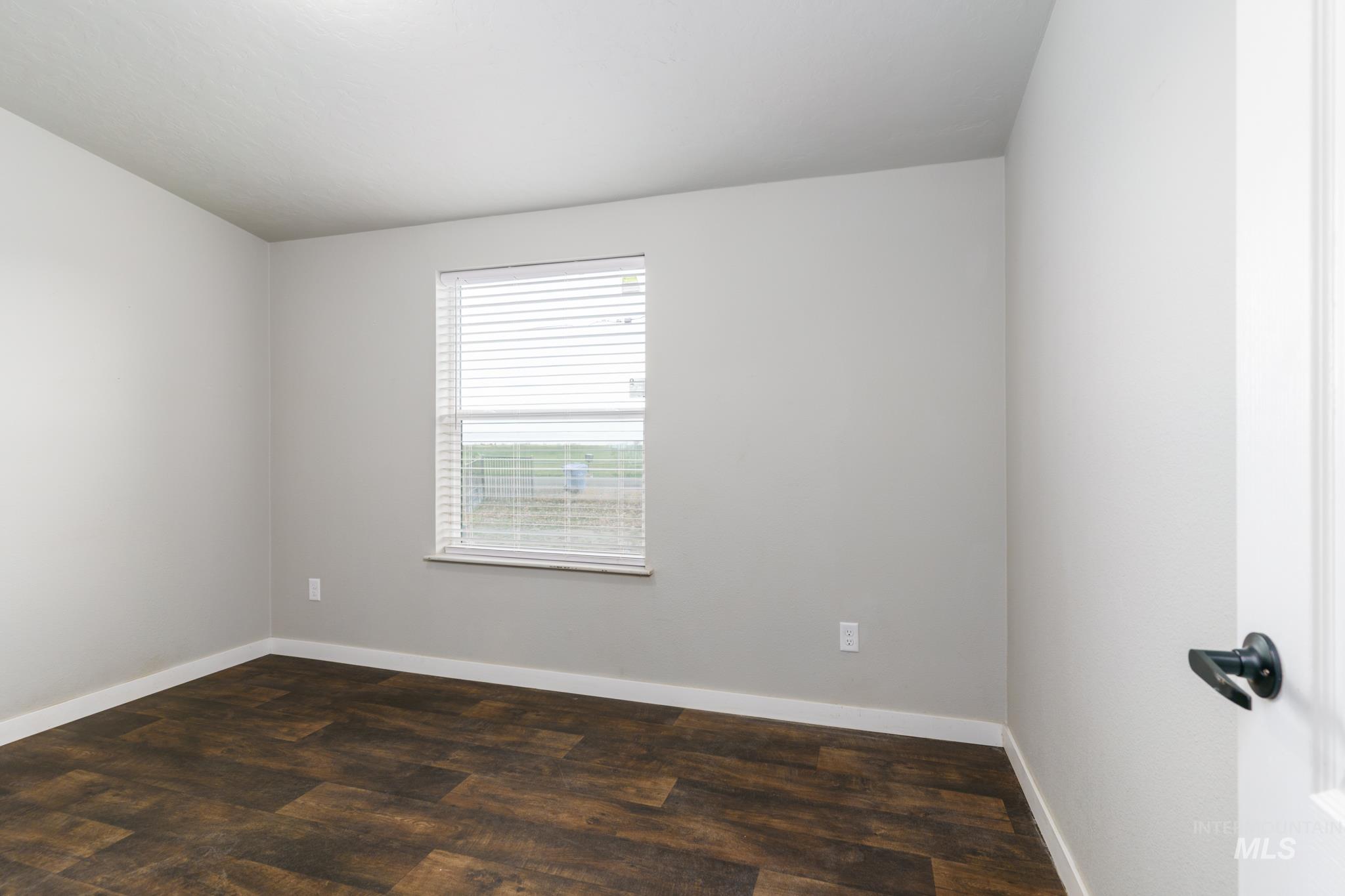 13678 North Hawthorne Road Pocatello, ID 83202 - Photo 18 of 37 Spare room with dark wood-style flooring and baseboards