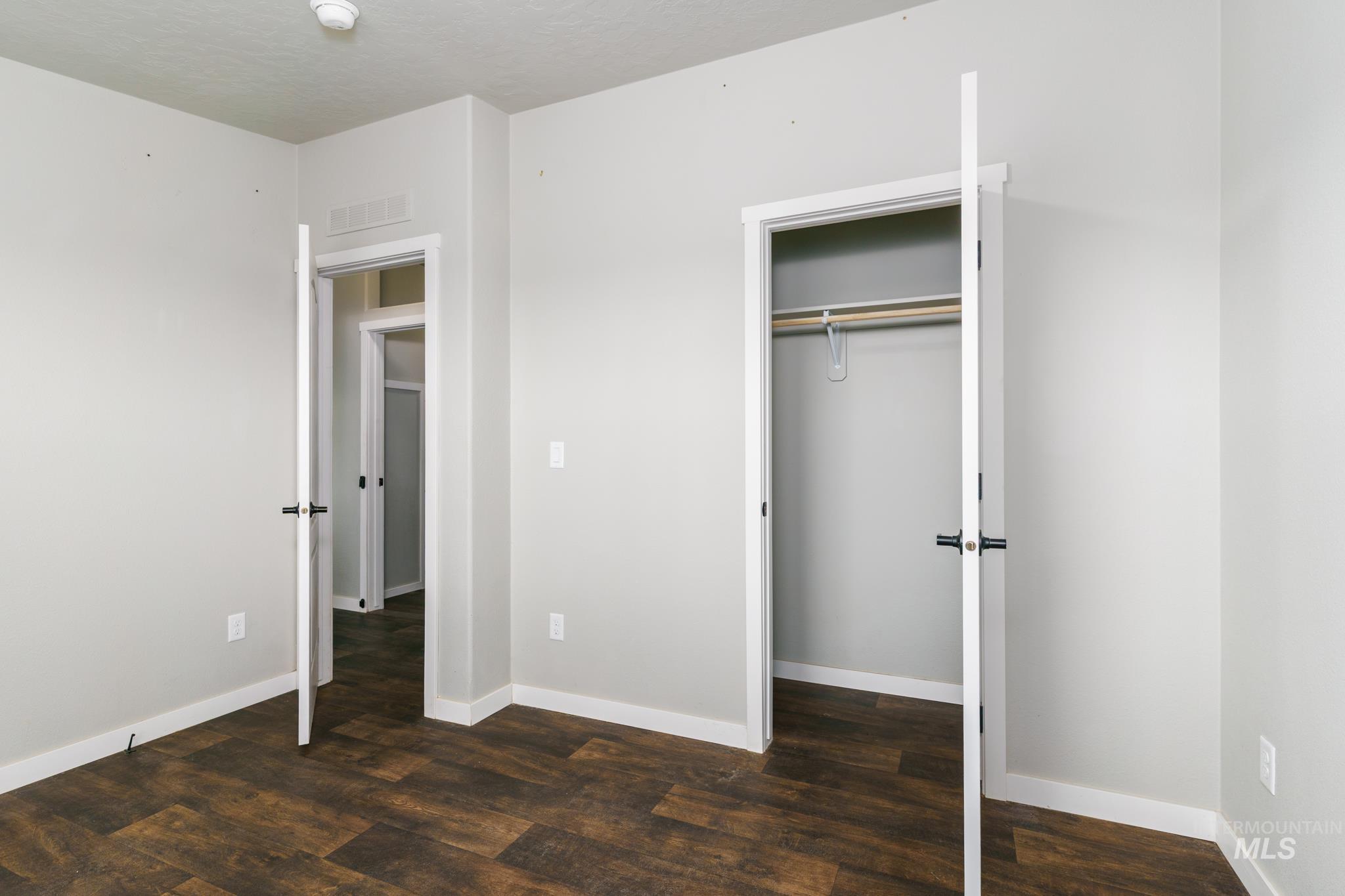 13678 North Hawthorne Road Pocatello, ID 83202 - Photo 19 of 37 Unfurnished bedroom with dark wood-style floors, a closet, and a textured ceiling