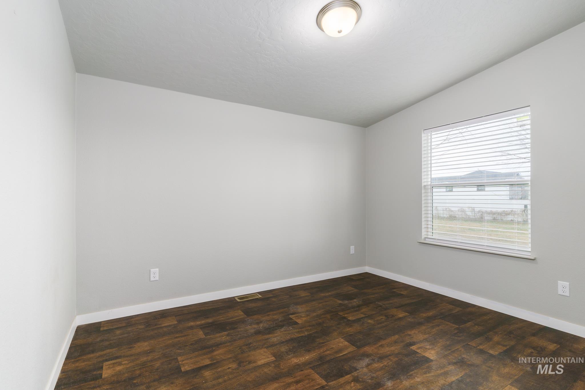13678 North Hawthorne Road Pocatello, ID 83202 - Photo 24 of 37 Spare room with lofted ceiling and dark wood-type flooring