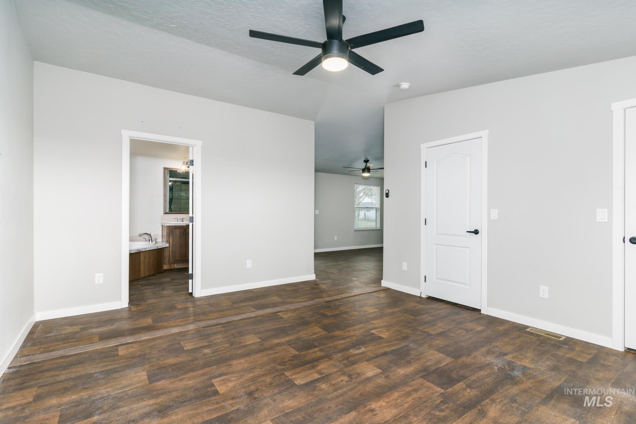 13678 North Hawthorne Road Pocatello, ID 83202 - Photo 25 of 37 Unfurnished bedroom featuring ensuite bath, dark wood-style flooring, ceiling fan, and a textured ceiling