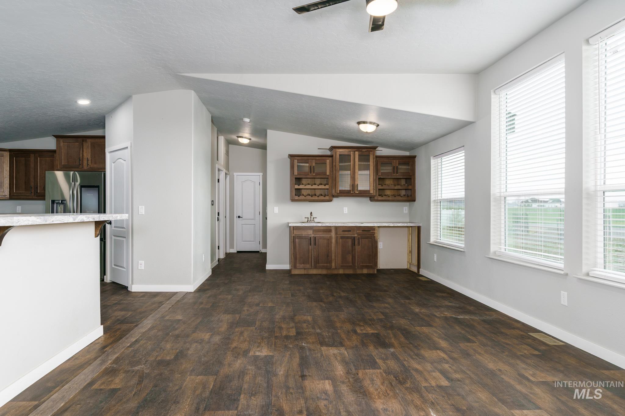 13678 North Hawthorne Road Pocatello, ID 83202 - Photo 10 of 37 Kitchen with vaulted ceiling, dark wood-style floors, glass insert cabinets, dark brown cabinets, and stainless steel fridge