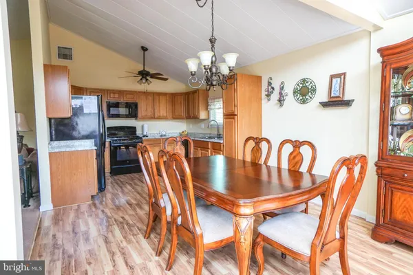 a kitchen with stainless steel appliances granite countertop wooden cabinets a sink a stove a refrigerator and island with wooden floor