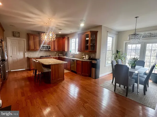 a kitchen with stainless steel appliances granite countertop a stove a refrigerator a dining table and chairs with wooden floor