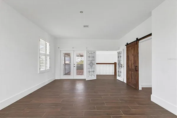 a view of an empty room with a window and wooden floor