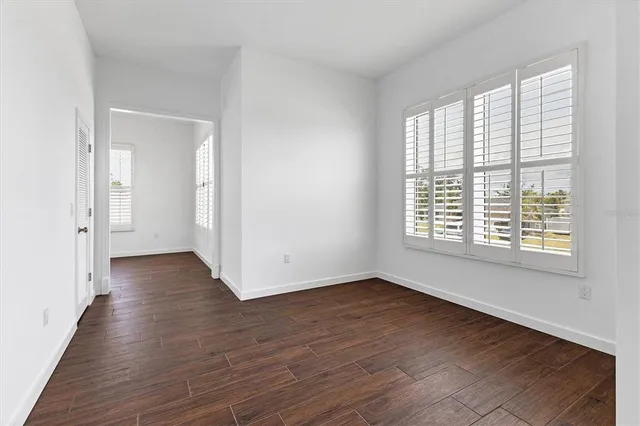 a view of an empty room with wooden floor and a window