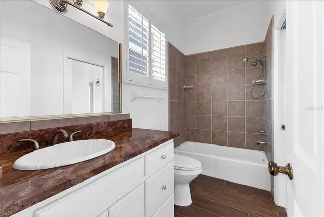 a bathroom with a granite countertop sink toilet a mirror and bathtub