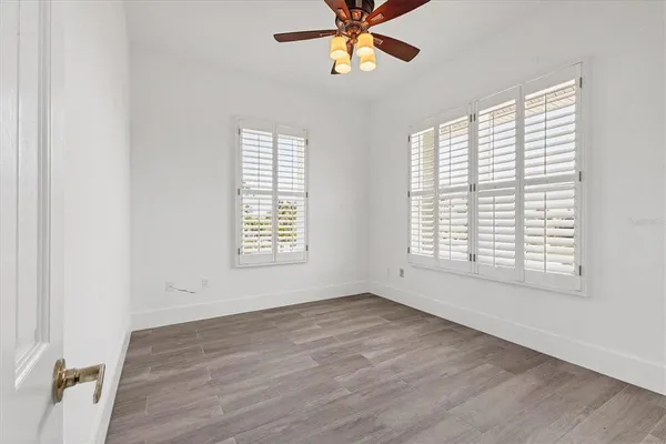 a view of an empty room with a window and wooden floor