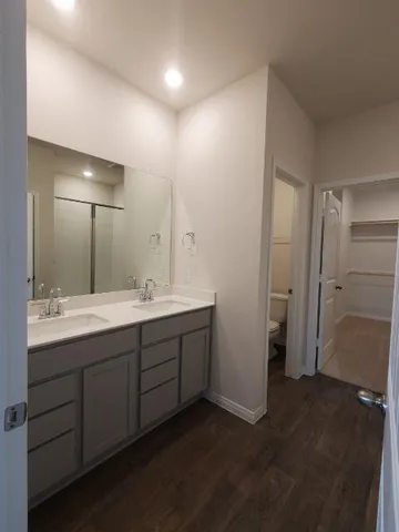 an empty room with wooden floor and windows with curtains